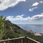 Siedlung auf grünem Hang, steil abfallend zum Meer